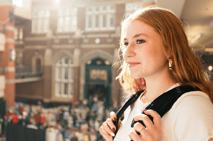 A student with long red hair stands at the balcony of the Stan Grad Centre, looking thoughtfully off-camera