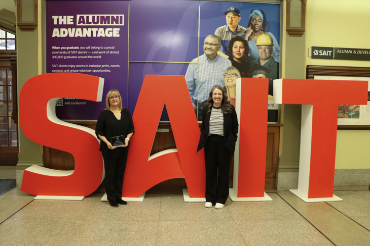 Two people pose with SAIT letters