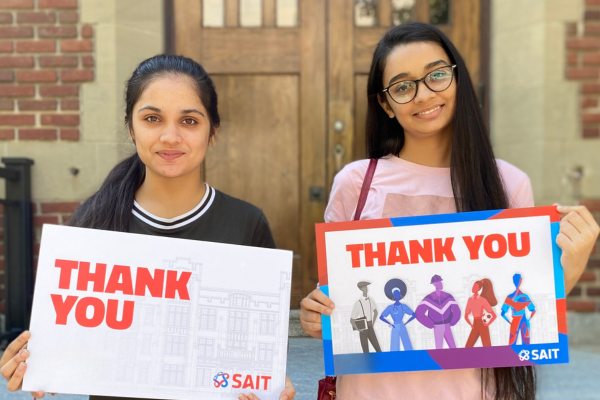 student standing outdoors with thank you signs