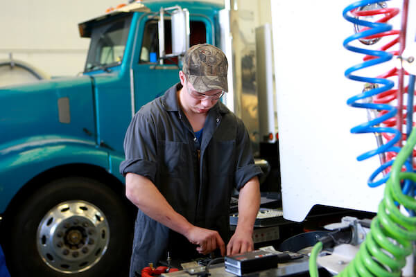 A heavy equipment technician student works on machinery.